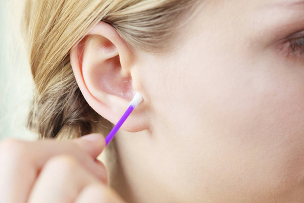 Concepto de higiene. Mujer joven limpiando oreja con hisopos de algodón de cerca - Foto, Imagen