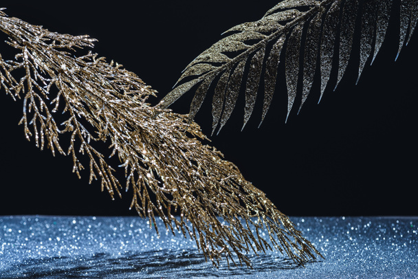 festive branches decorated by golden glitter over sparkling surface on black - Fotoğraf, Görsel