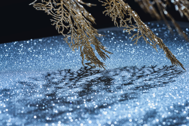 selective focus of festive branch decorated by golden glitter and shadow, christmas background concept - Photo, Image