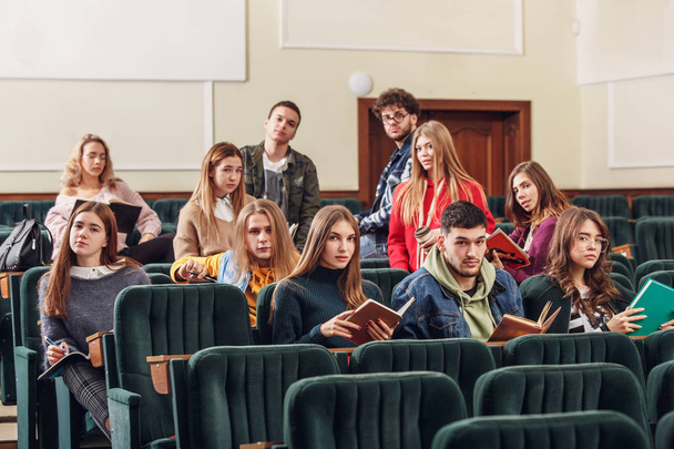 Neşeli mutlu öğrencilerin ders önce bir konferans salonunda oturan Grup - Fotoğraf, Görsel