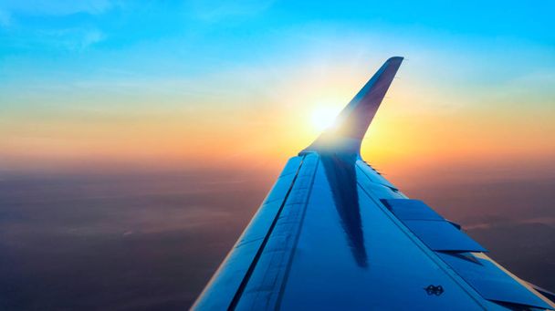 Avion d'aile en altitude pendant le vol. Coucher ou lever de soleil avec nuages, rayons lumineux et autres effets atmosphériques
 . - Photo, image