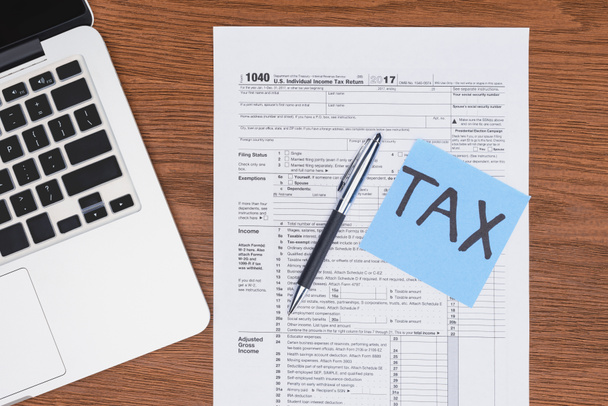 bovenaanzicht van belasting formulier-, laptop- en blauwe kaart met "fiscaal" woord op Bureau - Foto, afbeelding