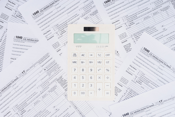 vista superior da calculadora branca com formulários fiscais em segundo plano
  - Foto, Imagem