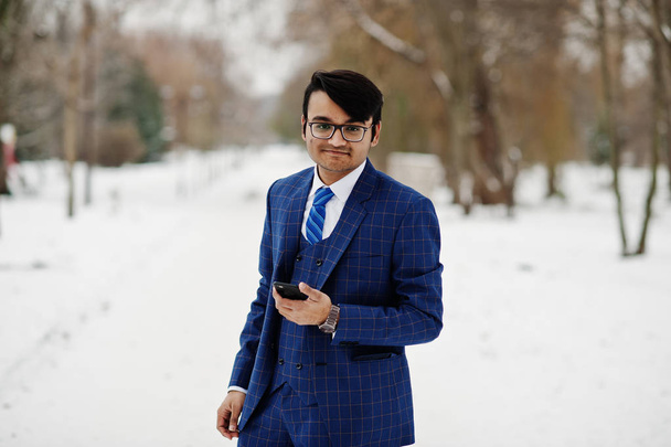 Stylish indian business man in suit and glasses posed at winter day outdoor, with mobile phone at  hand. - Fotó, kép