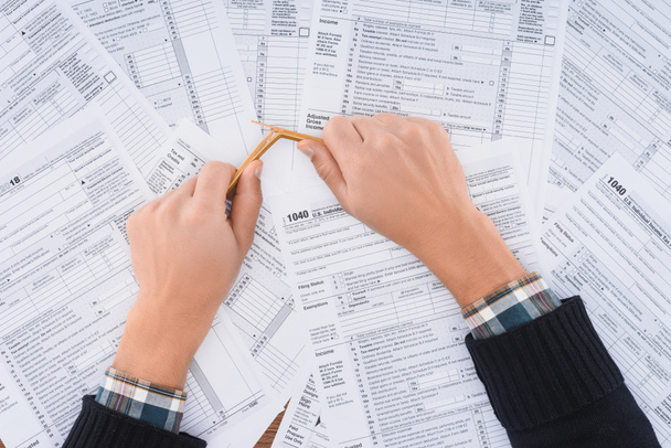 Ausgeschnittene Ansicht eines gestressten Mannes, der Bleistift mit Steuerformularen im Hintergrund bricht - Foto, Bild
