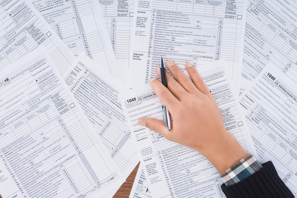 vue recadrée d'un homme tenant un stylo et remplissant des formulaires fiscaux avec espace de copie
 - Photo, image