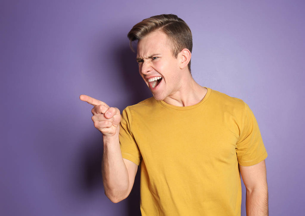 Portrait of aggressive young man on color background - Фото, изображение