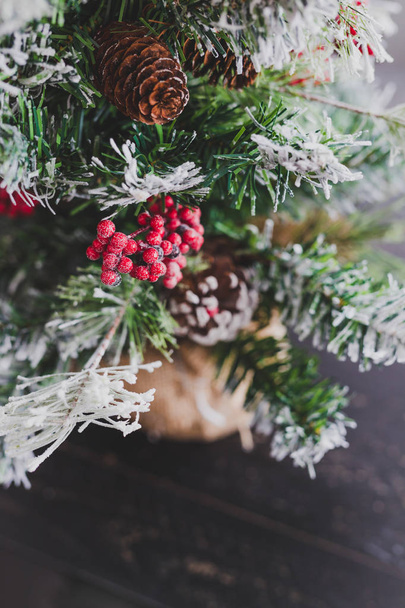 Kerstboom met dennenappels en mistletoes bessen en hints van sneeuw op de takken, cozy feestelijke wintervakantie gevoel - Foto, afbeelding