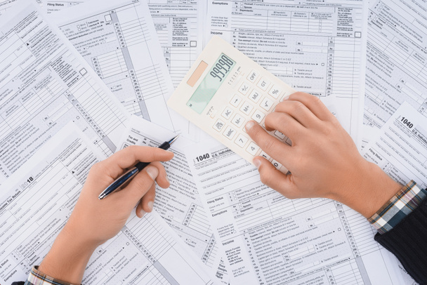 vista recortada del hombre llenando formularios de impuestos y utilizando la calculadora
  - Foto, Imagen