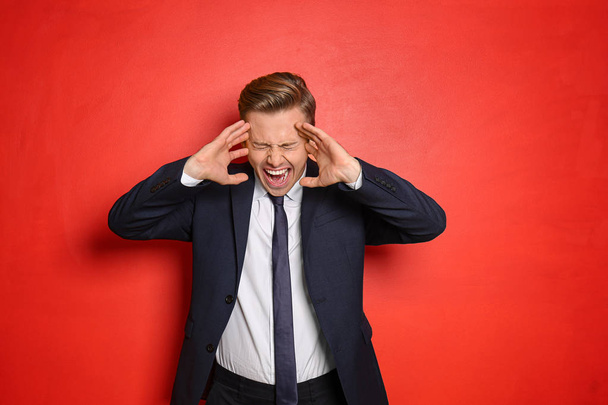 Portrait of screaming young businessman on color background - Photo, Image