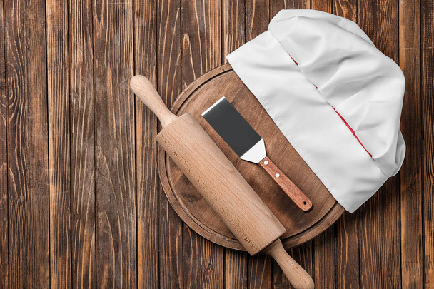Sombrero de chef con utensilios de cocina sobre mesa de madera
 - Foto, Imagen