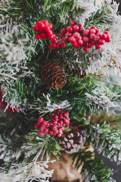 Christmas tree with pine cones and mistletoes berries and hints of snow on the branches, cozy festive winter holidays feeling - Foto, afbeelding