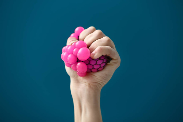 Weibliche Hand drückt Stressball auf farbigem Hintergrund - Foto, Bild