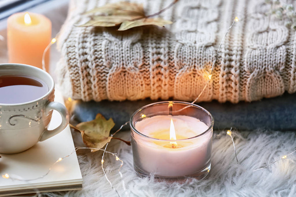 Красива осіння композиція з палаючими свічками і чашкою чаю на підвіконні
 - Фото, зображення