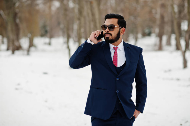 Stylish indian beard business man in suit and sunglasses posed at winter day outdoor, speaking on mobile phone. - Фото, зображення