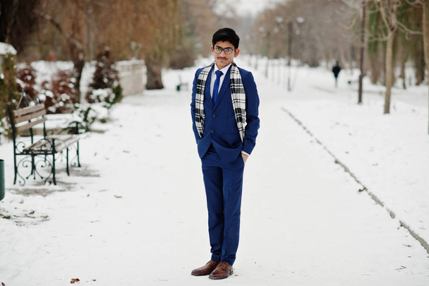 Élégant étudiant indien homme en costume, lunettes et écharpe posé à la journée d'hiver en plein air
. - Photo, image