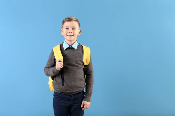 Cute little schoolboy with backpack on color background - Fotó, kép