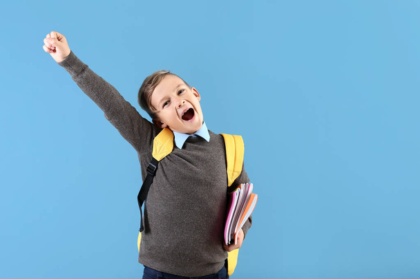 Happy little schoolboy with backpack on color background - Photo, Image