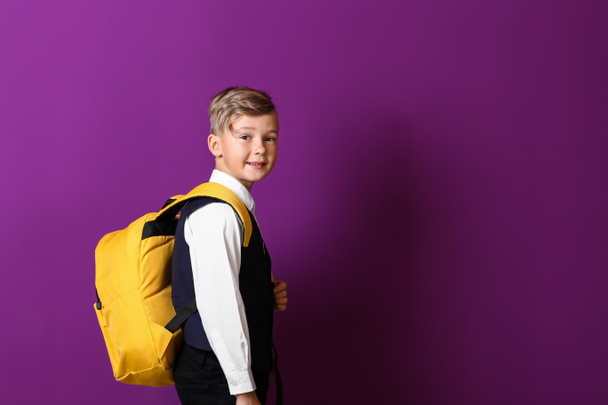 Cute little schoolboy with backpack on color background - Photo, image