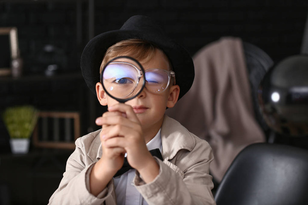 Cute little detective with magnifying glass indoors - Foto, Imagen