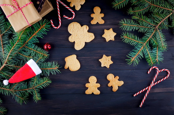 Christmas composition with many gingerbread, fir branhes and gift box on dark wooden table. Holiday concept background, top view, copy spase - Foto, afbeelding