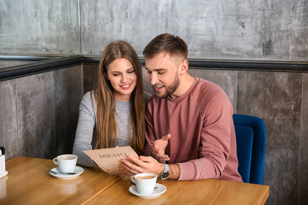 Young couple looking through menu in restaurant - Foto, Imagen