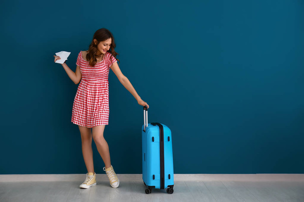 Female tourist with luggage near color wall - Photo, image