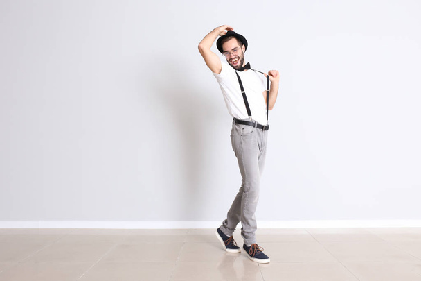 Csinos, fiatal férfi táncol, fehér fal közelében - Fotó, kép