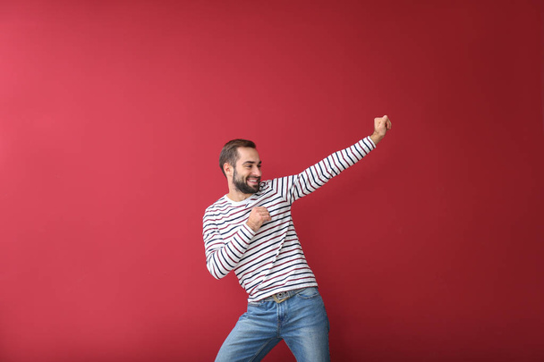 Handsome young man dancing on color background - Photo, Image