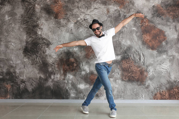 Handsome young man dancing near grunge wall - Фото, зображення