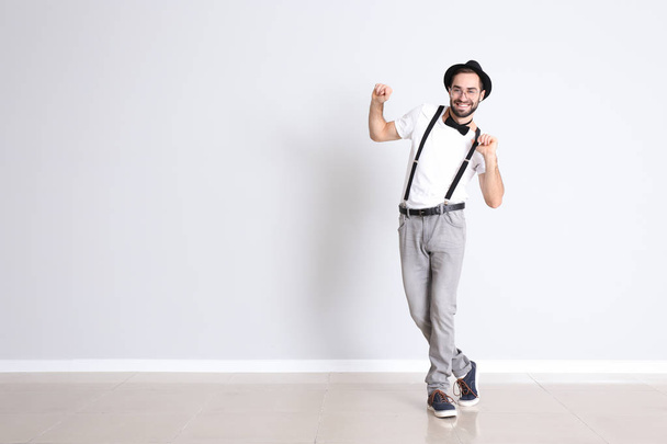Csinos, fiatal férfi táncol, fehér fal közelében - Fotó, kép