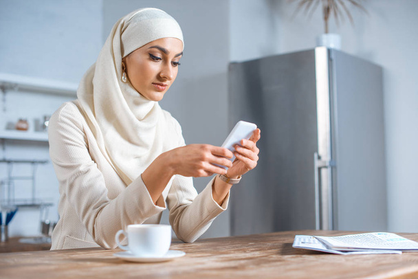 красива молода мусульманка використовує смартфон вдома
  - Фото, зображення