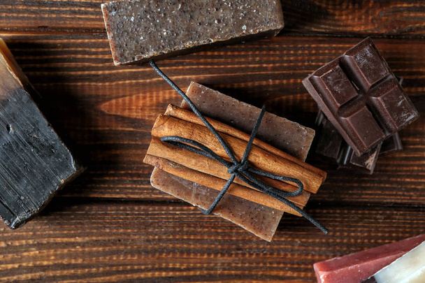 Zeep bars met kaneelstokjes en chocolade op houten tafel - Foto, afbeelding