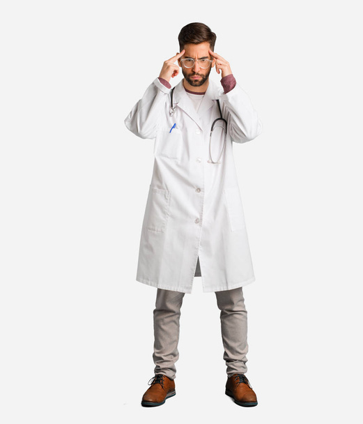 Young doctor man doing a concentration gesture - Fotoğraf, Görsel