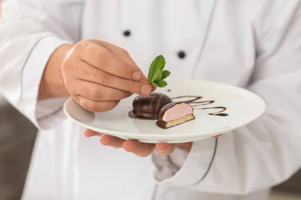 Чоловічий шеф-кухар зі смачним десертом на кухні, крупним планом
 - Фото, зображення