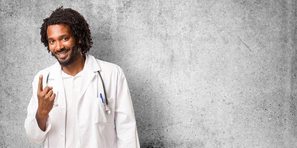 Bonito médico afro-americano mostrando o número um, símbolo da contagem, conceito de matemática, confiante e alegre
 - Foto, Imagem