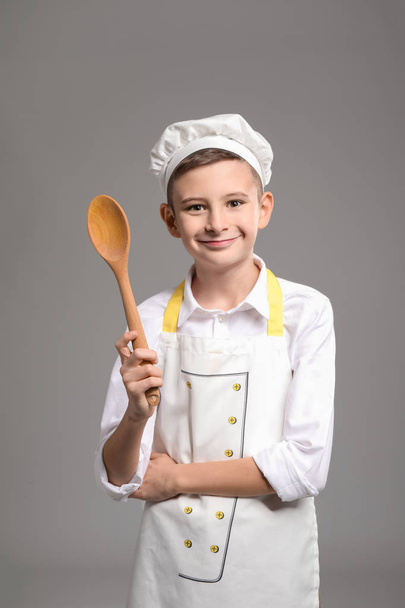 Cute little chef with spoon on grey background - Foto, imagen