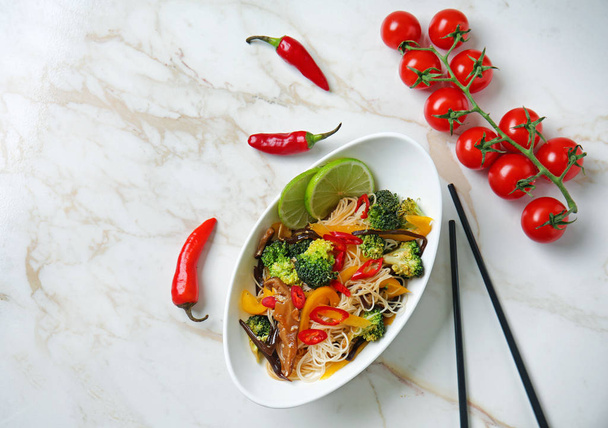 Prato com macarrão chinês saboroso e legumes na mesa, vista superior
 - Foto, Imagem