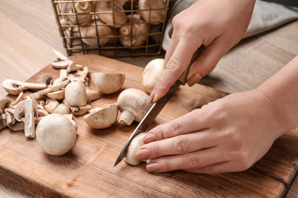 Женщина режет сырые грибы на деревянной доске
 - Фото, изображение