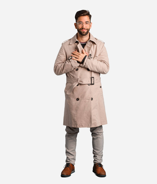 Young man wearing trench coat doing a romantic gesture - Foto, immagini