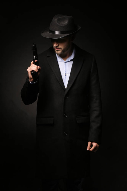 Detective with gun on dark background - Photo, Image