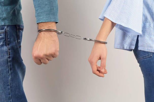 Couple with handcuffed together hands on light background. Concept of addiction - Photo, image