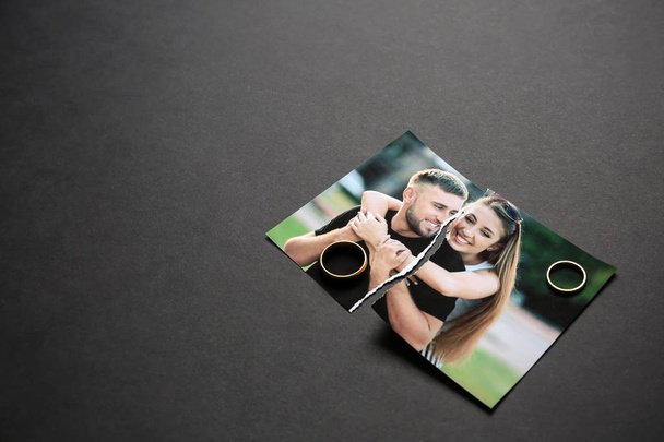 Torn photo of happy couple with rings on dark background. Concept of divorce - Fotó, kép