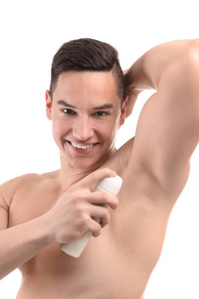Young man using deodorant on white background - Photo, image