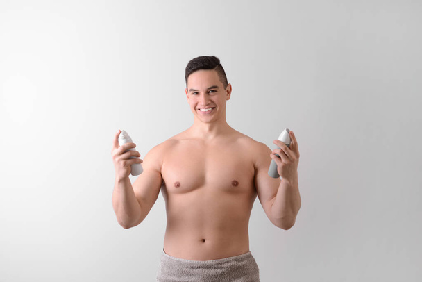 Młody człowiek z Dezodoranty na jasnym tle - Zdjęcie, obraz