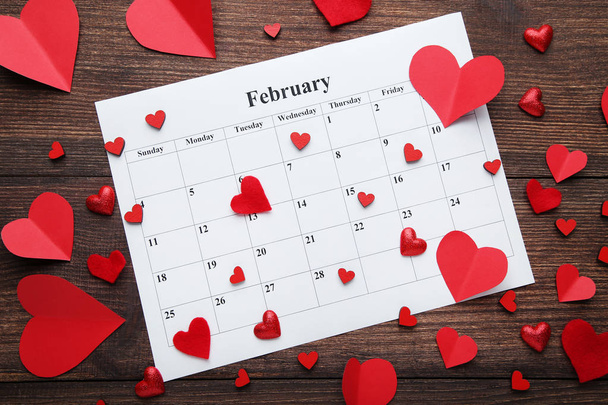 Red hearts with white february calendar on wooden table - Fotó, kép