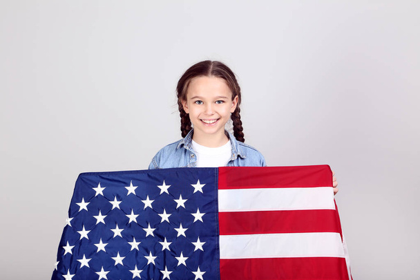 girl holding an American flag on grey background - Фото, изображение