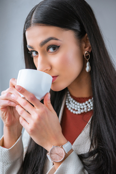 beautiful young woman drinking coffee and looking at camera - Fotografie, Obrázek