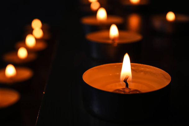 Burning candles on table in darkness, closeup - Foto, imagen