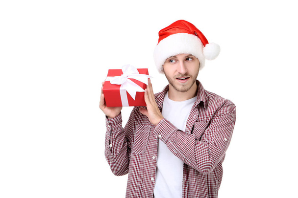 Young man in santa hat holding gift box isolated on white background - Foto, Imagem